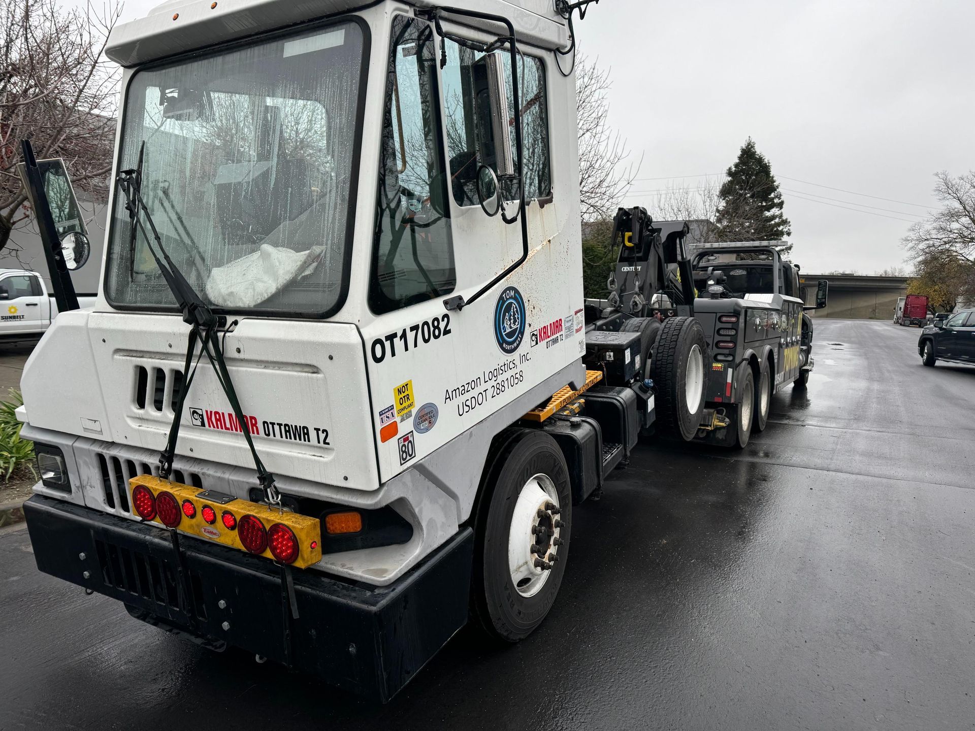 A white tow truck is parked on the side of the road.