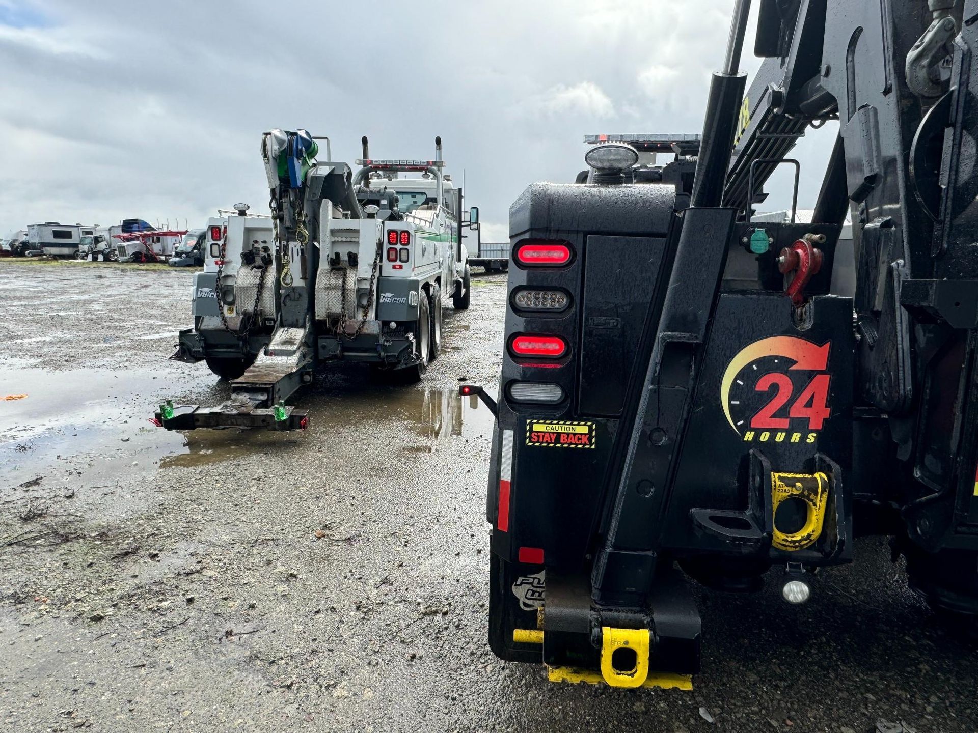 A tow truck with the number 24 on the back is parked in a parking lot.