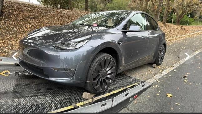 A tesla model y is being towed by a tow truck.