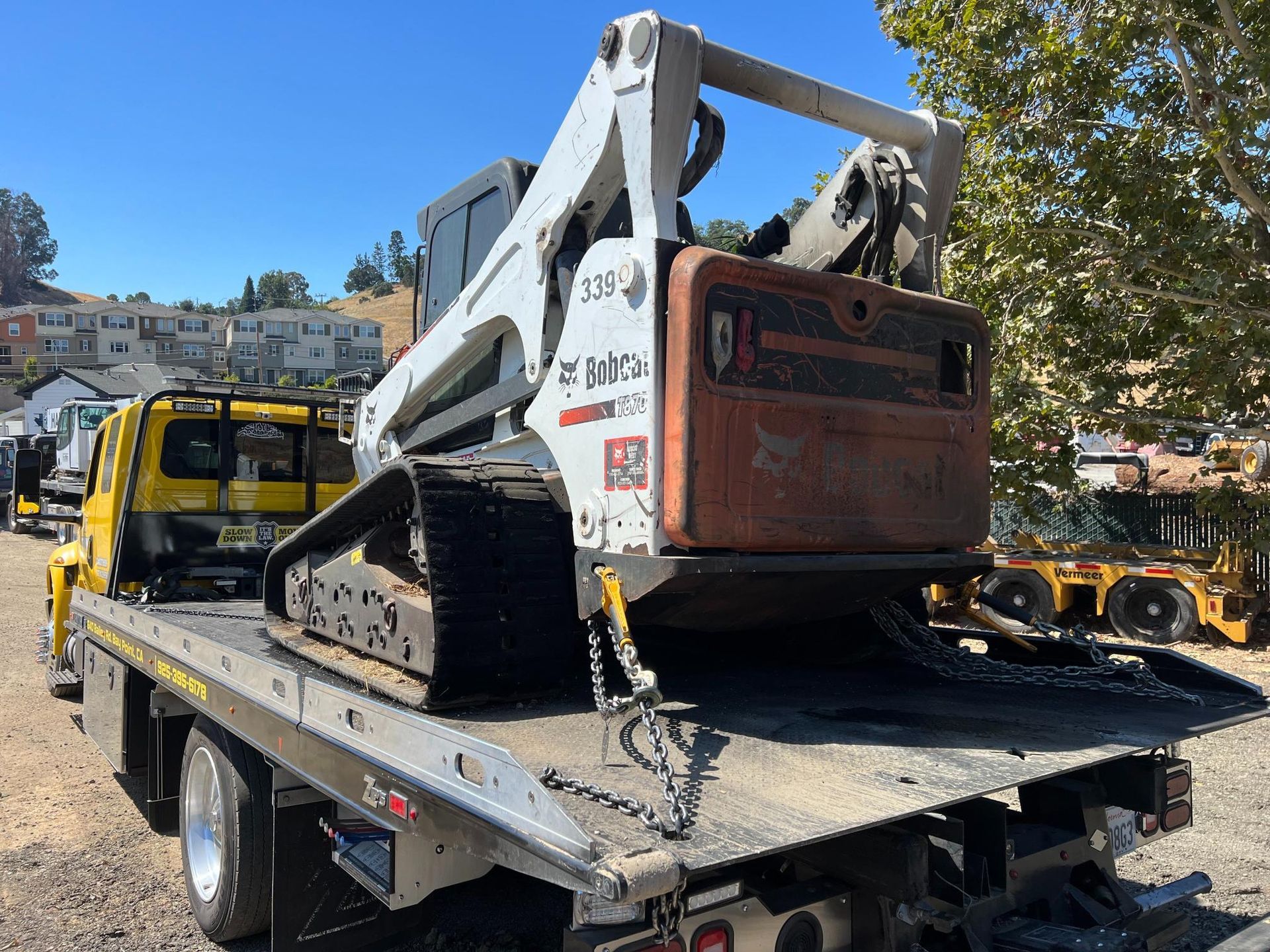 A bulldozer is sitting on top of a tow truck.