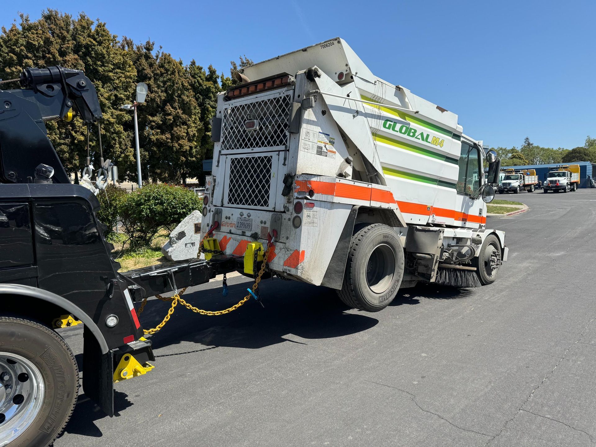 A garbage truck is being towed by a tow truck.