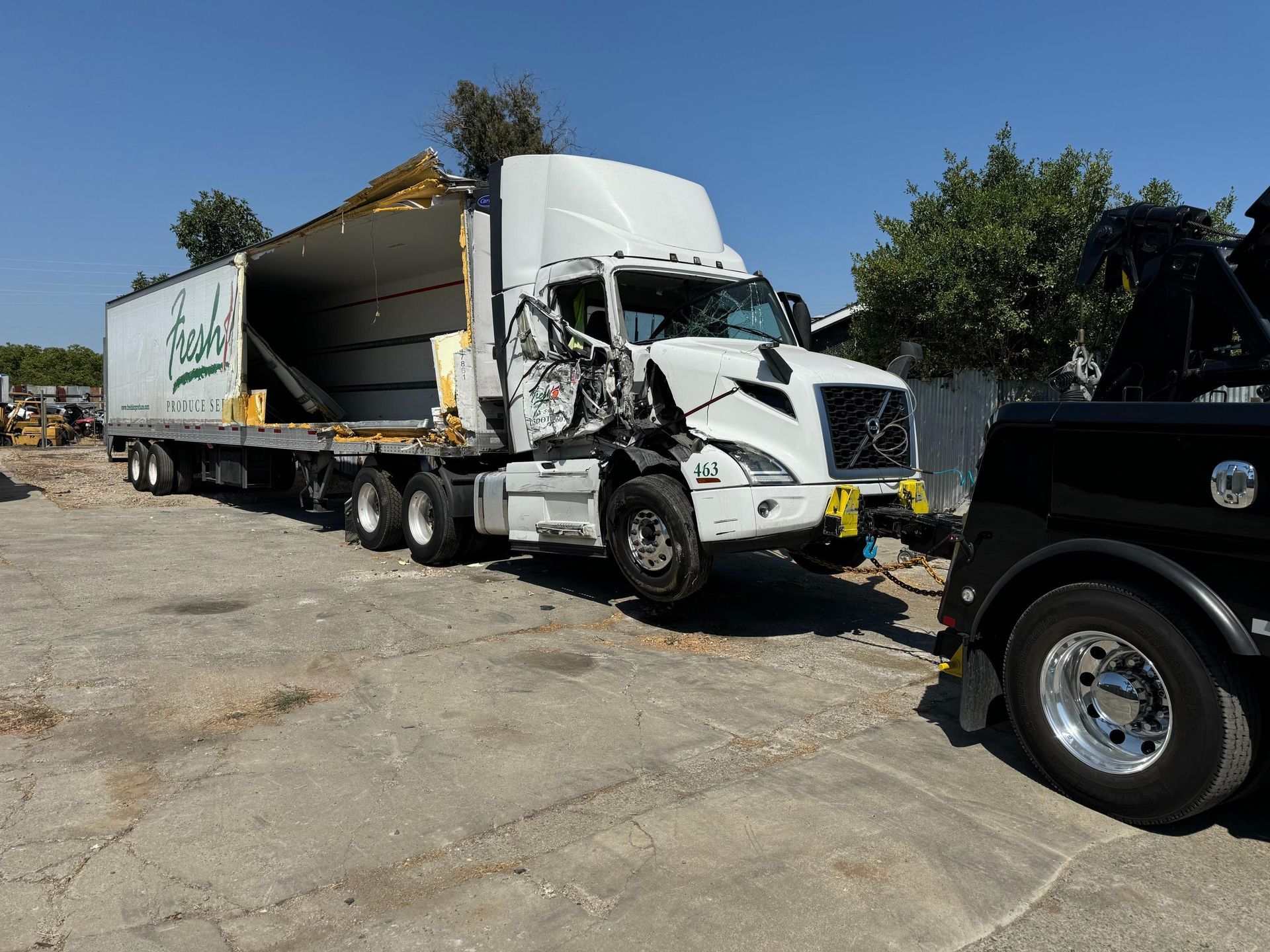 A semi truck is being towed by a tow truck in a parking lot.