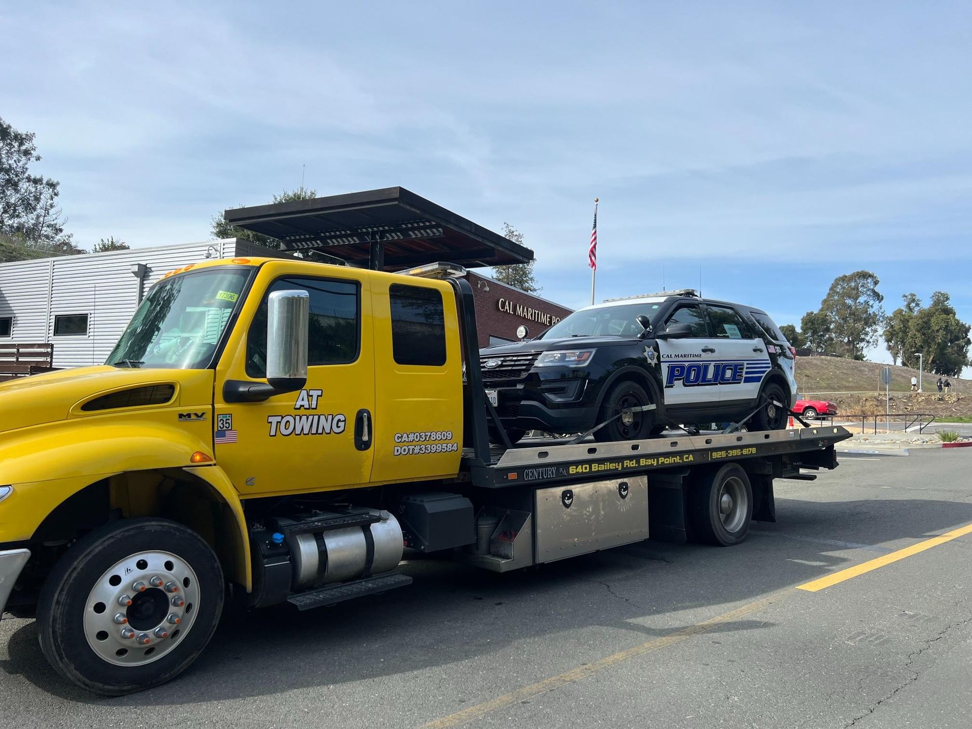 A yellow tow truck is towing a police car.
