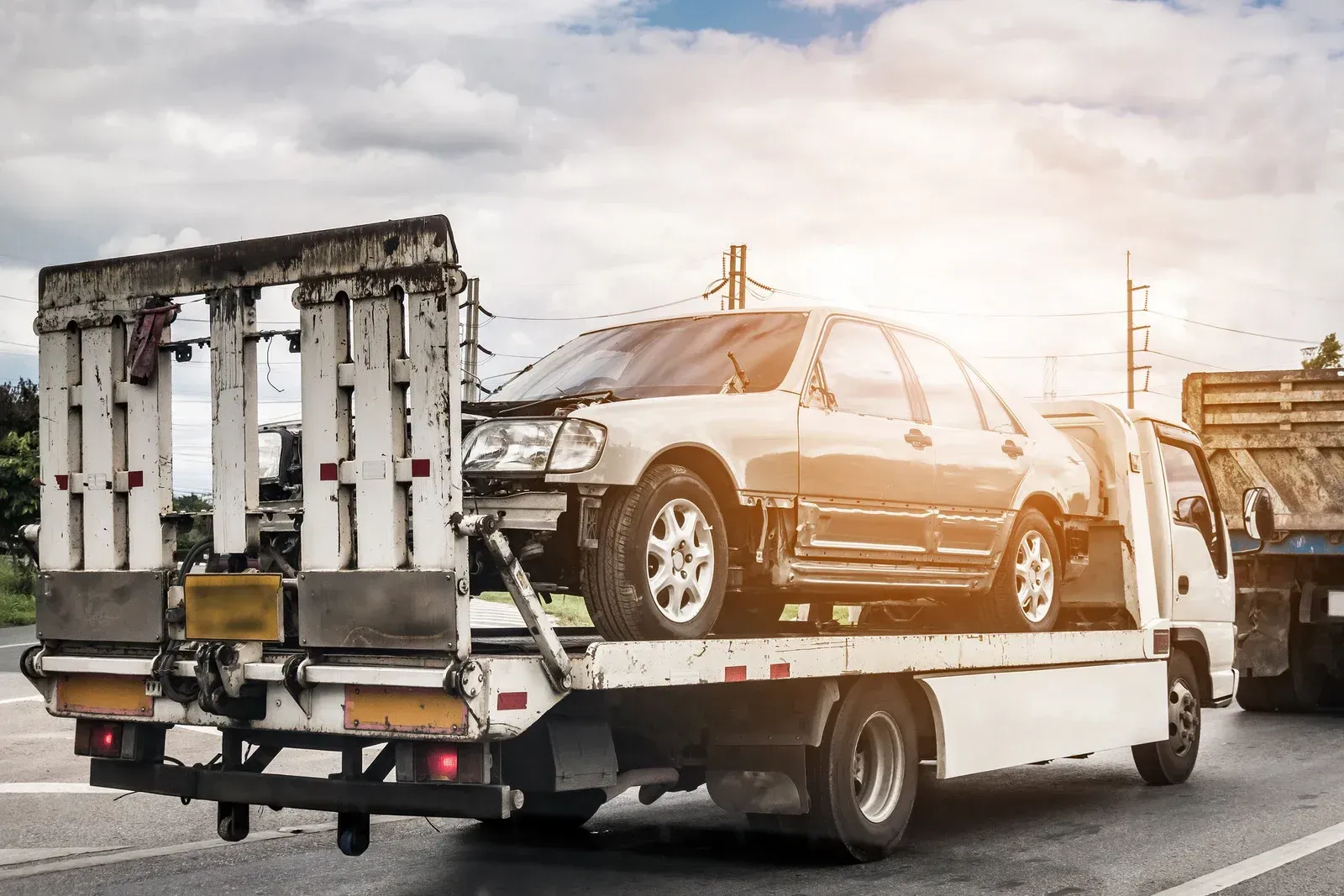 A car is being towed by a tow truck on the side of the road.
