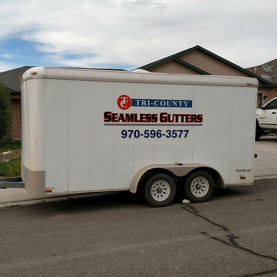 A white trailer with tri-county seamless gutters written on it