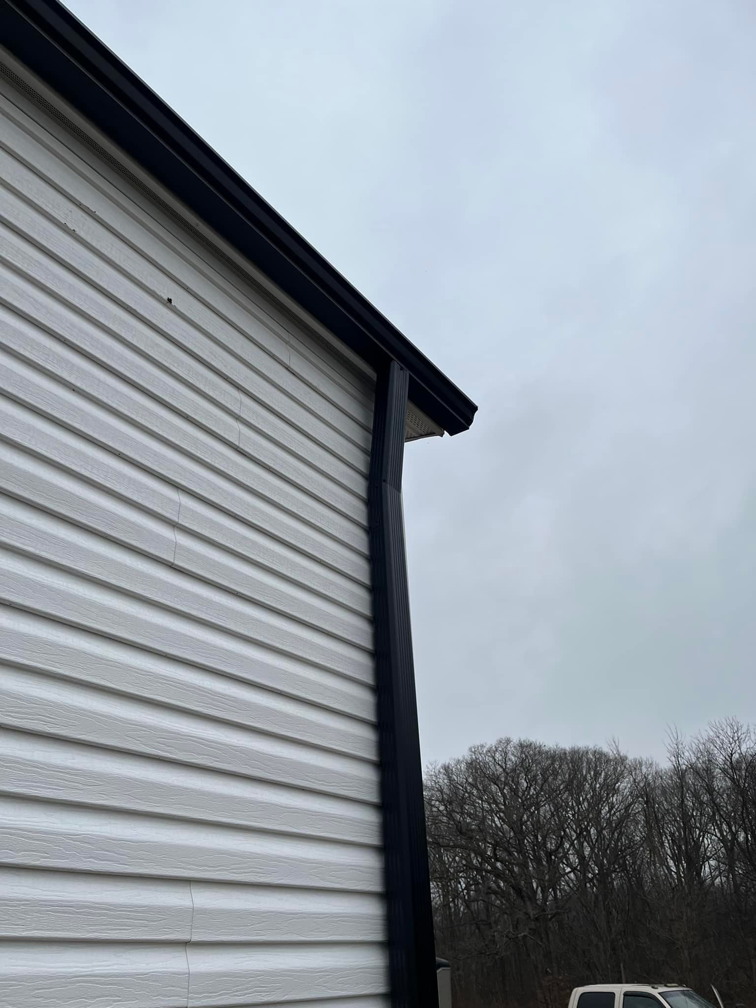 A white building with a black gutter on the side of it.
