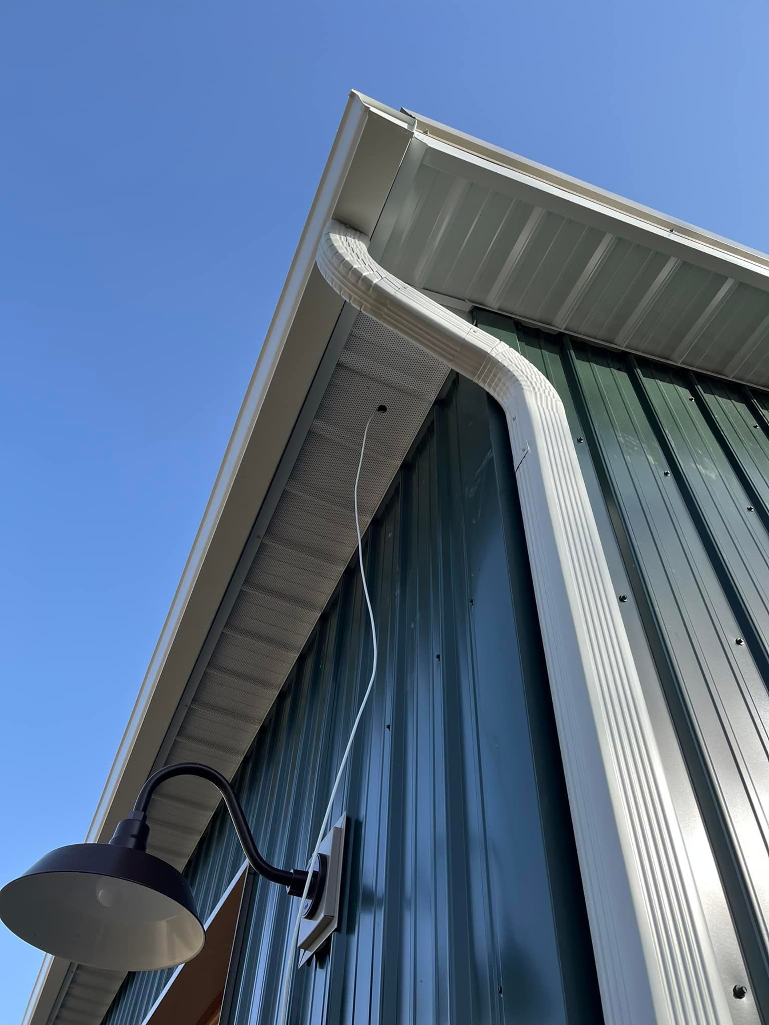 A white building with a black gutter on the side of it.