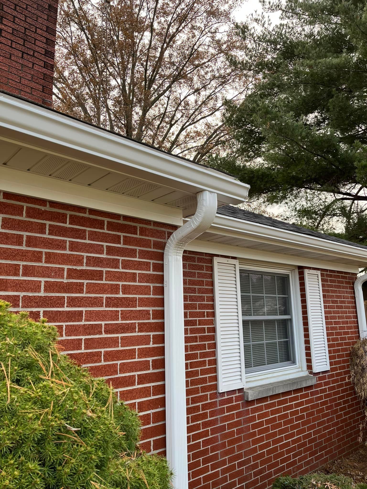 A red brick house with a white gutter and shutters.