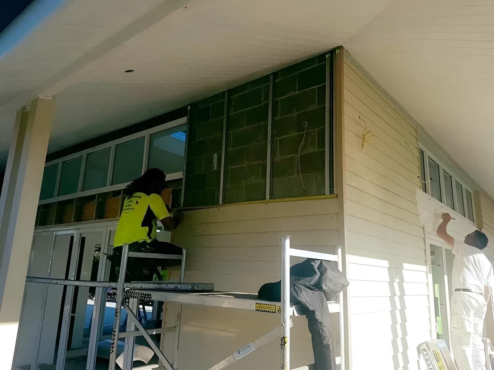 A Man is Sitting on a Ladder Working on a Building — Aspex Construction - Lou Pieren In Port Macquarie, NSW