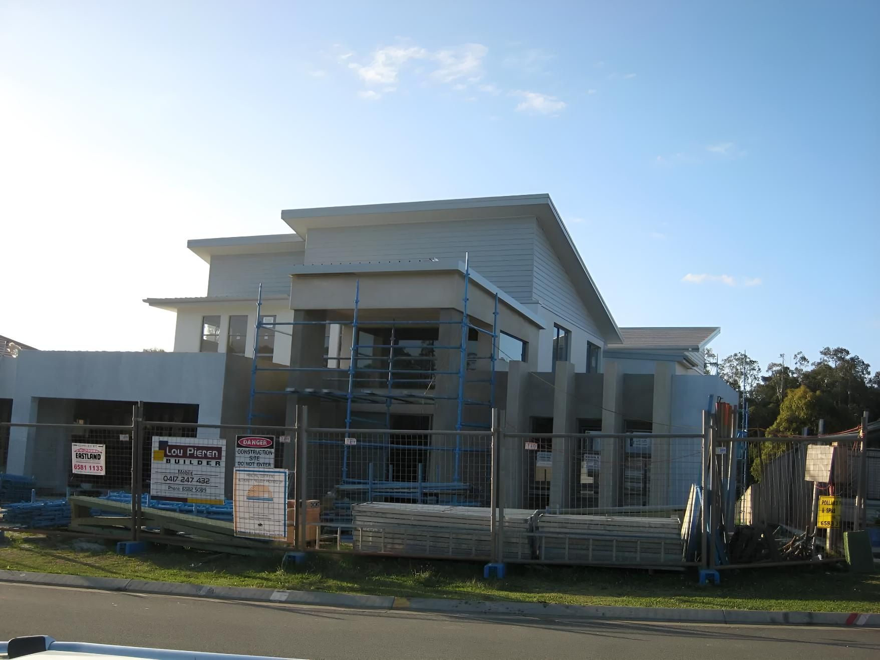 A Large House is Being Built With a Fence Around It — Aspex Construction - Lou Pieren In Wauchope, NSW