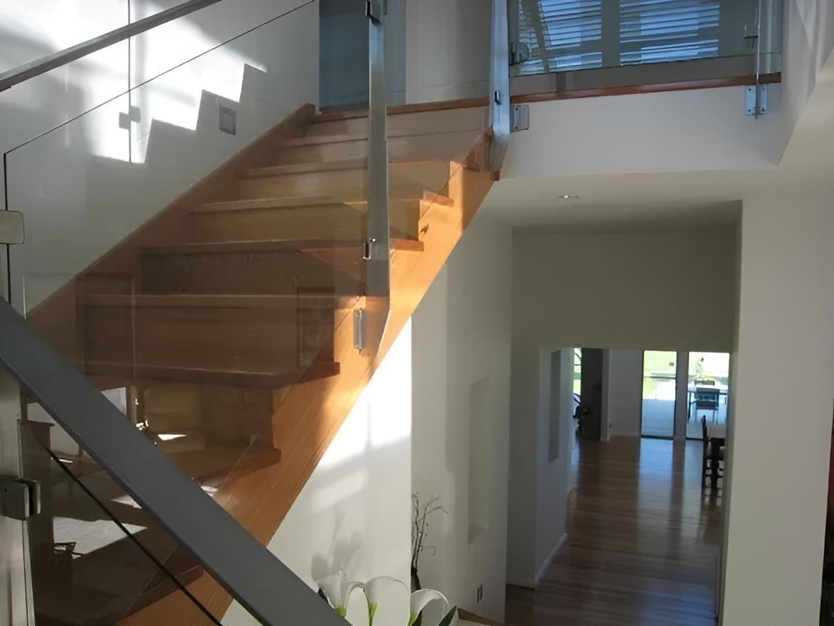 A Wooden Staircase With a Glass Railing in a Hallway — Aspex Construction - Lou Pieren In Port Macquarie, NSW