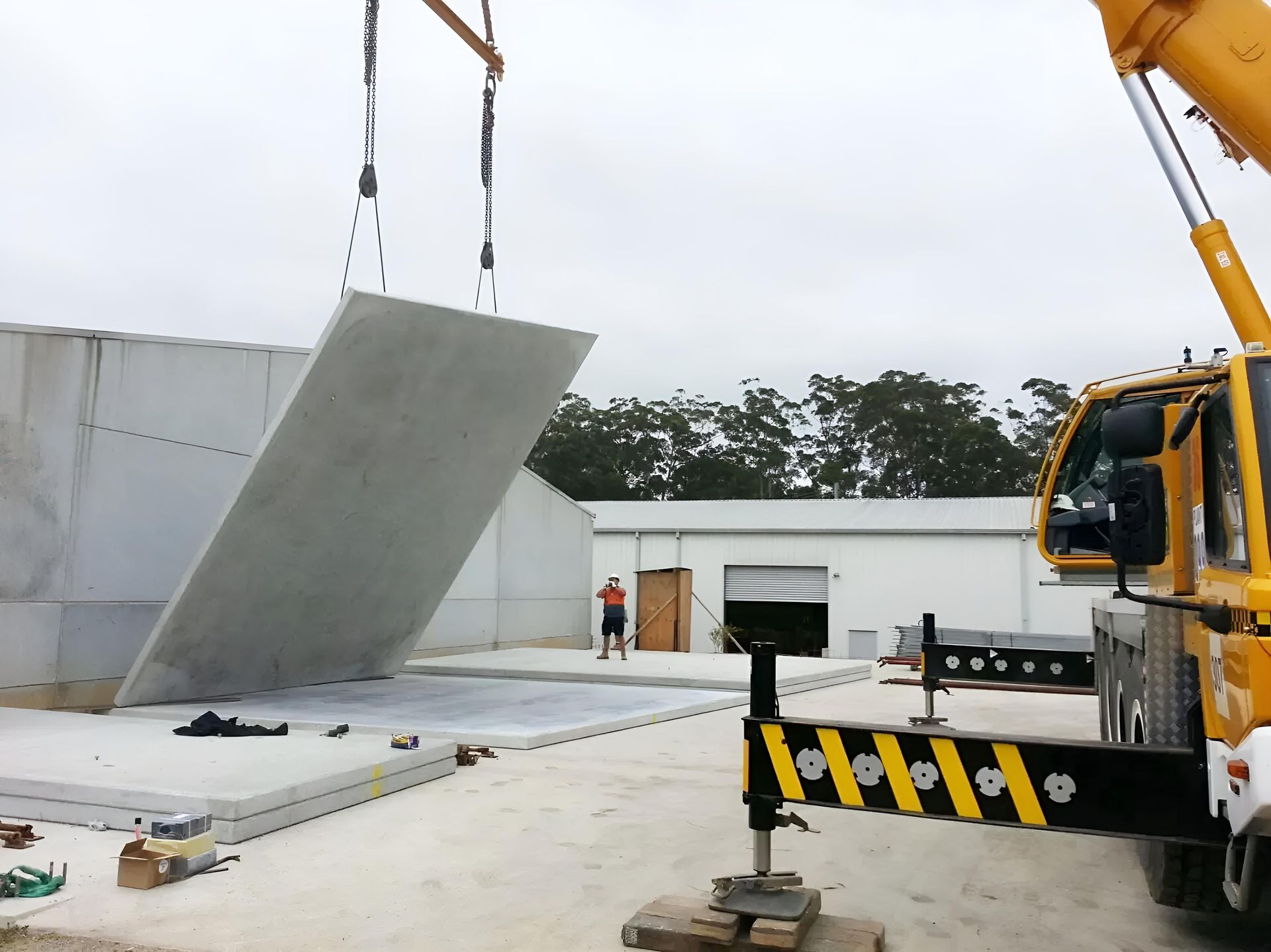 A Yellow Crane is Lifting a Large Piece of Concrete — Aspex Construction - Lou Pieren In Wauchope, NSW