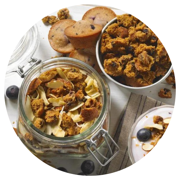 A jar of granola next to a bowl of muffins