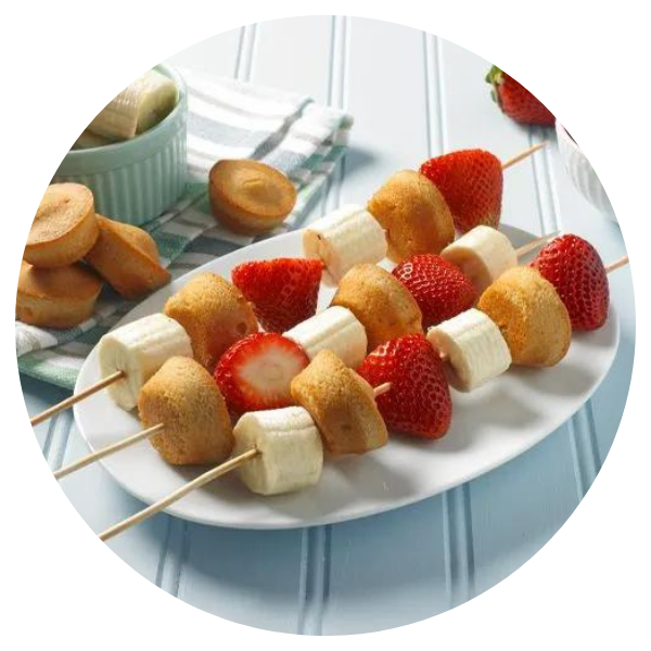 A white plate topped with bananas and strawberries on skewers