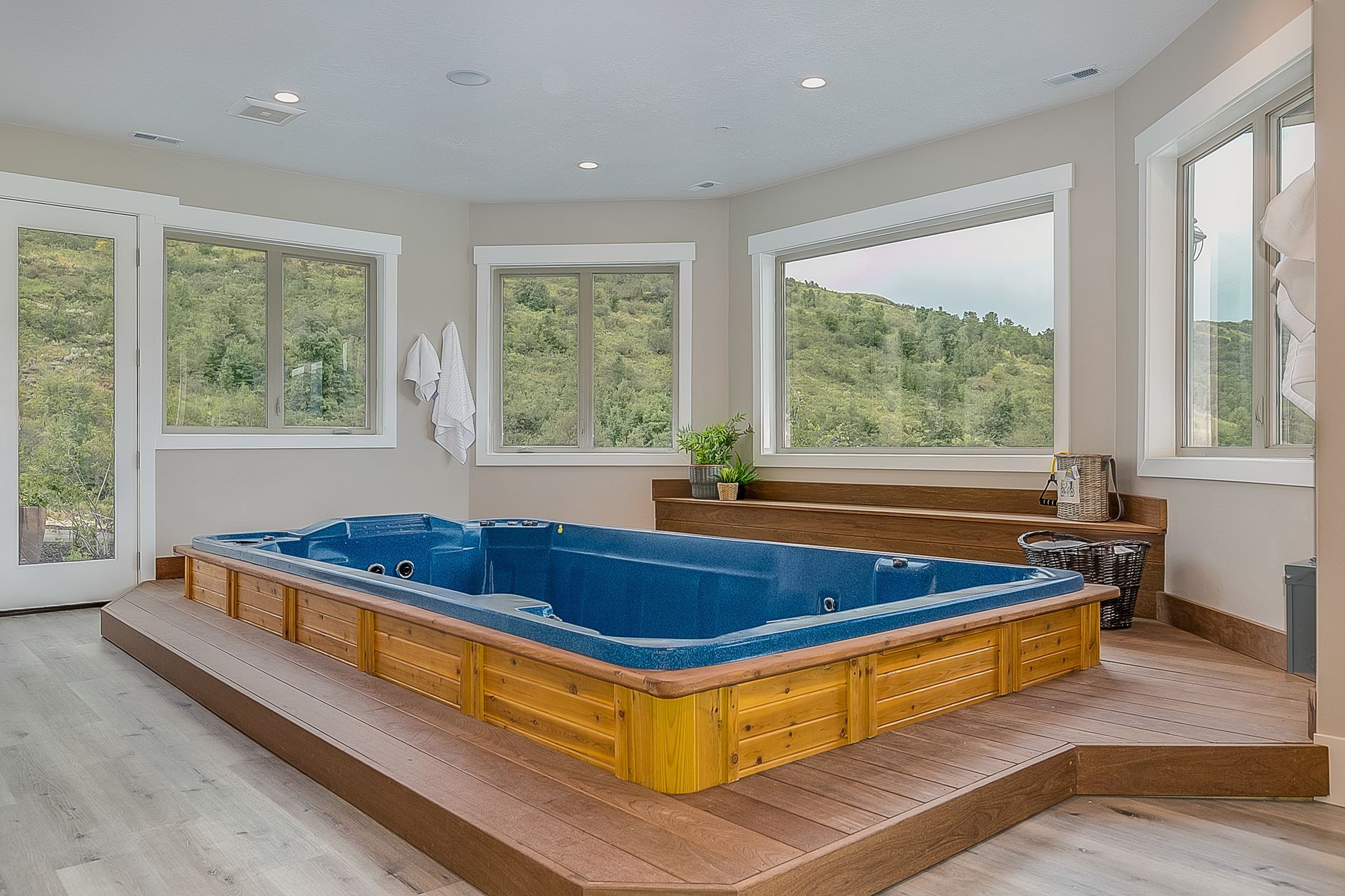 Luxury home interior featuring elevated blue jacuzzi for sale with wood panels and scenic views. Luxury home interior featuring elevated blue jacuzzi for sale with wood panels and scenic views.