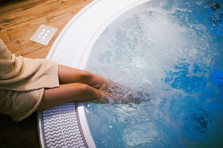 Woman entering spa, showcasing jacuzzi for sale with elegance with her feet in relaxing warm water.