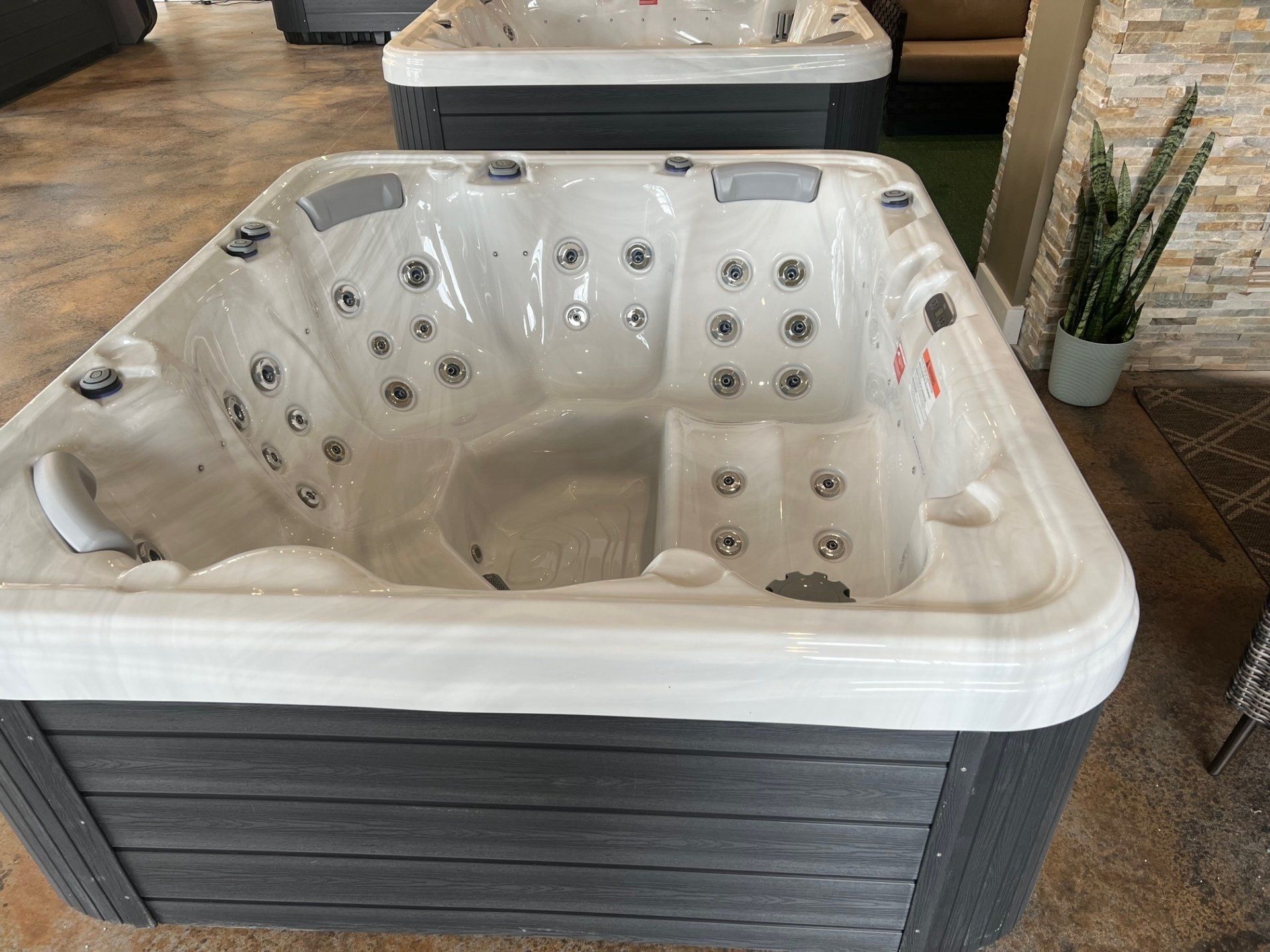 Hot tub with gray exterior, white interior, and jets on display at a store.