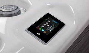 Close-up of a spa control panel. Black touch screen with colored icons. White spa surface.