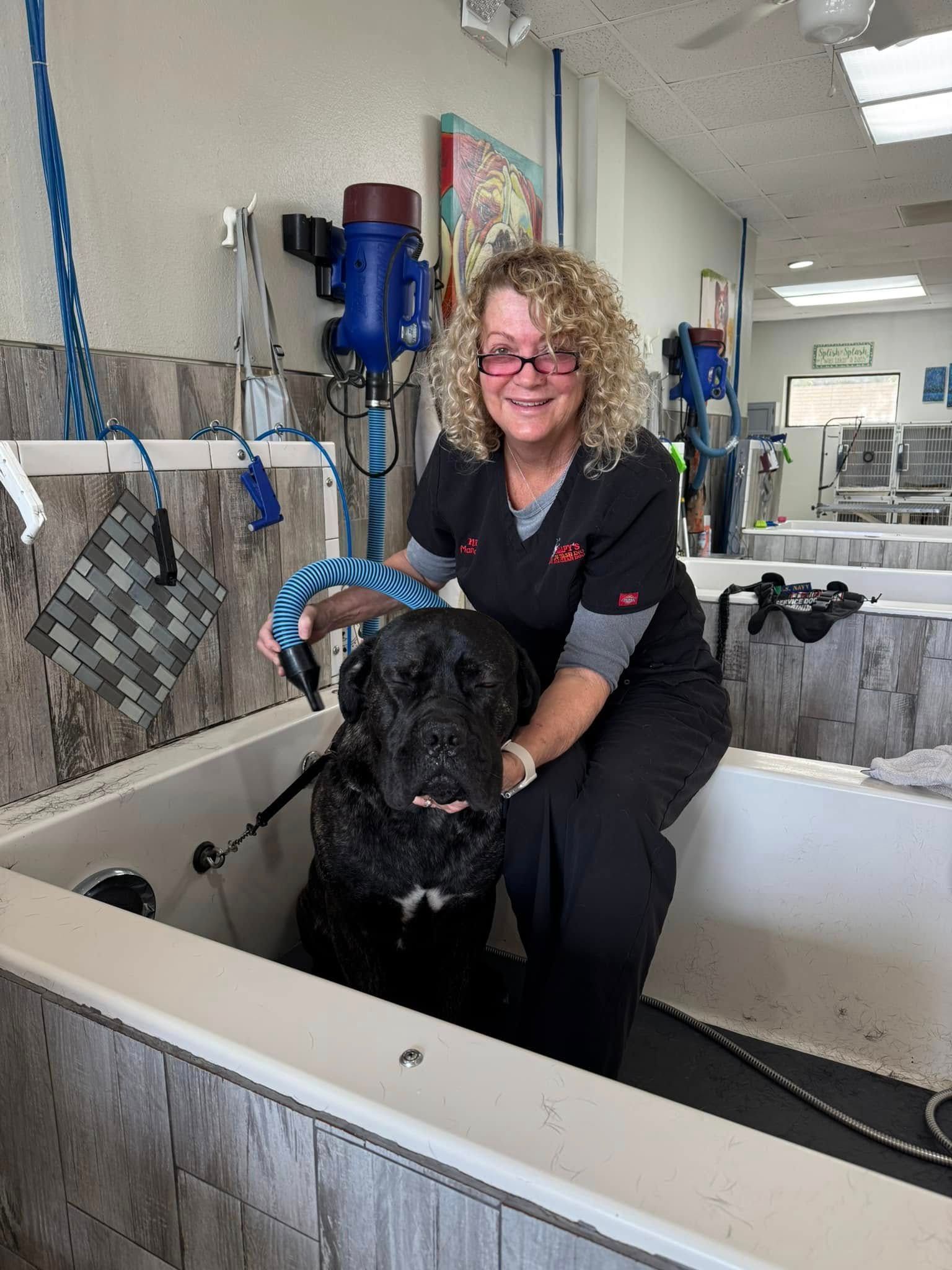 A woman is kneeling on a dog in a bathtub.