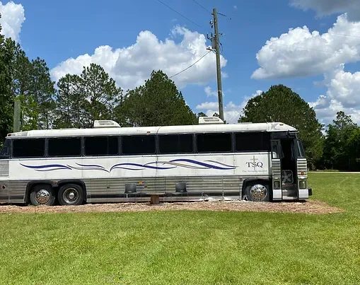 A large bus is parked in a grassy field.