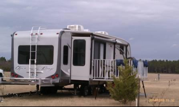 A white rv is parked in the middle of a field