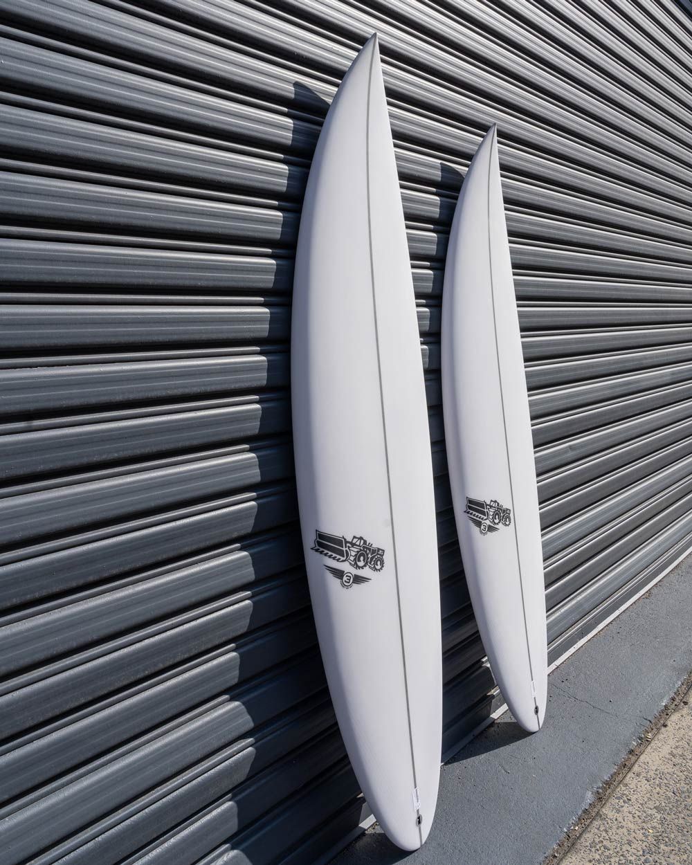 Two White Surfboards Are Leaning Against a Gray Wall — Slimes Boardstore in Erina, NSW