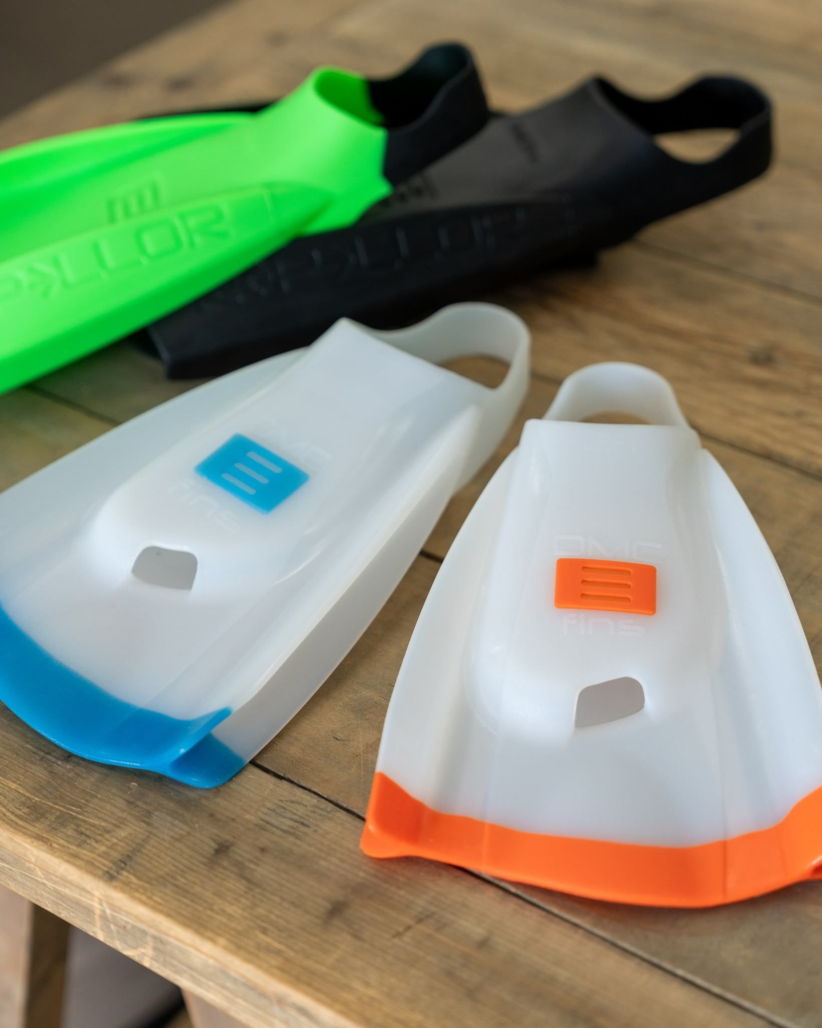 Four Different Colored Flippers Are Sitting on a Wooden Table — Slimes Boardstore in Lisarow, NSW