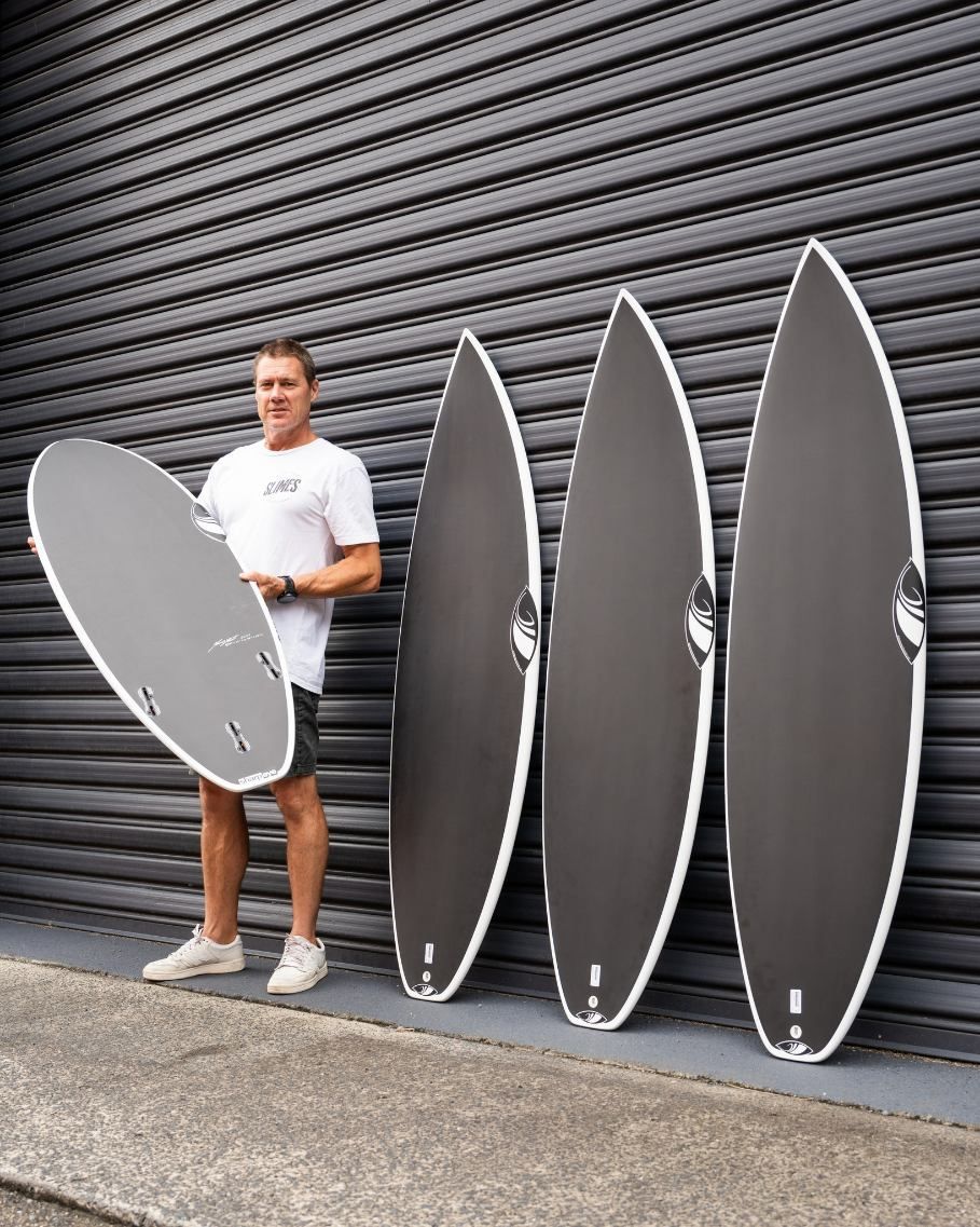 A Man is Standing Next to Four Surfboards Against a Wall — Slimes Boardstore in Lisarow, NSW