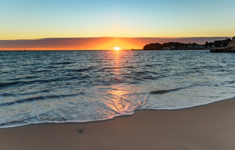 The Sun is Setting Over the Ocean on a Beach — Slimes Boardstore in Wyoming, NSW