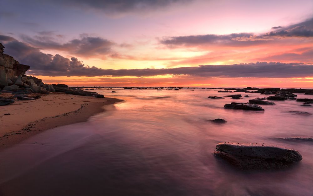 A Sunset Over a Beach with Rocks in The Water — Slimes Boardstore in Bateau Bay, NSW