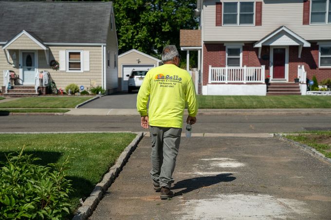 A man in a yellow shirt is walking down a driveway.