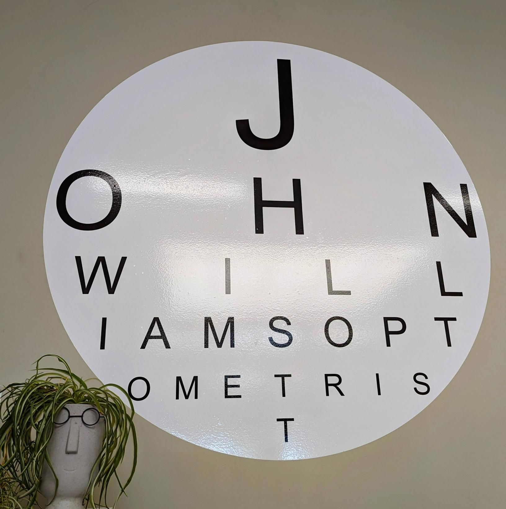 A Circle with The Letters J H N and L on It — John Williams Optometrist in Grafton, NSW