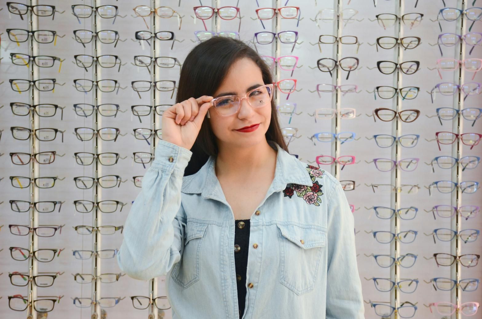 A Woman Is Wearing Glasses in Front of A Wall of Glasses — John Williams Optometrist in Grafton, NSW
