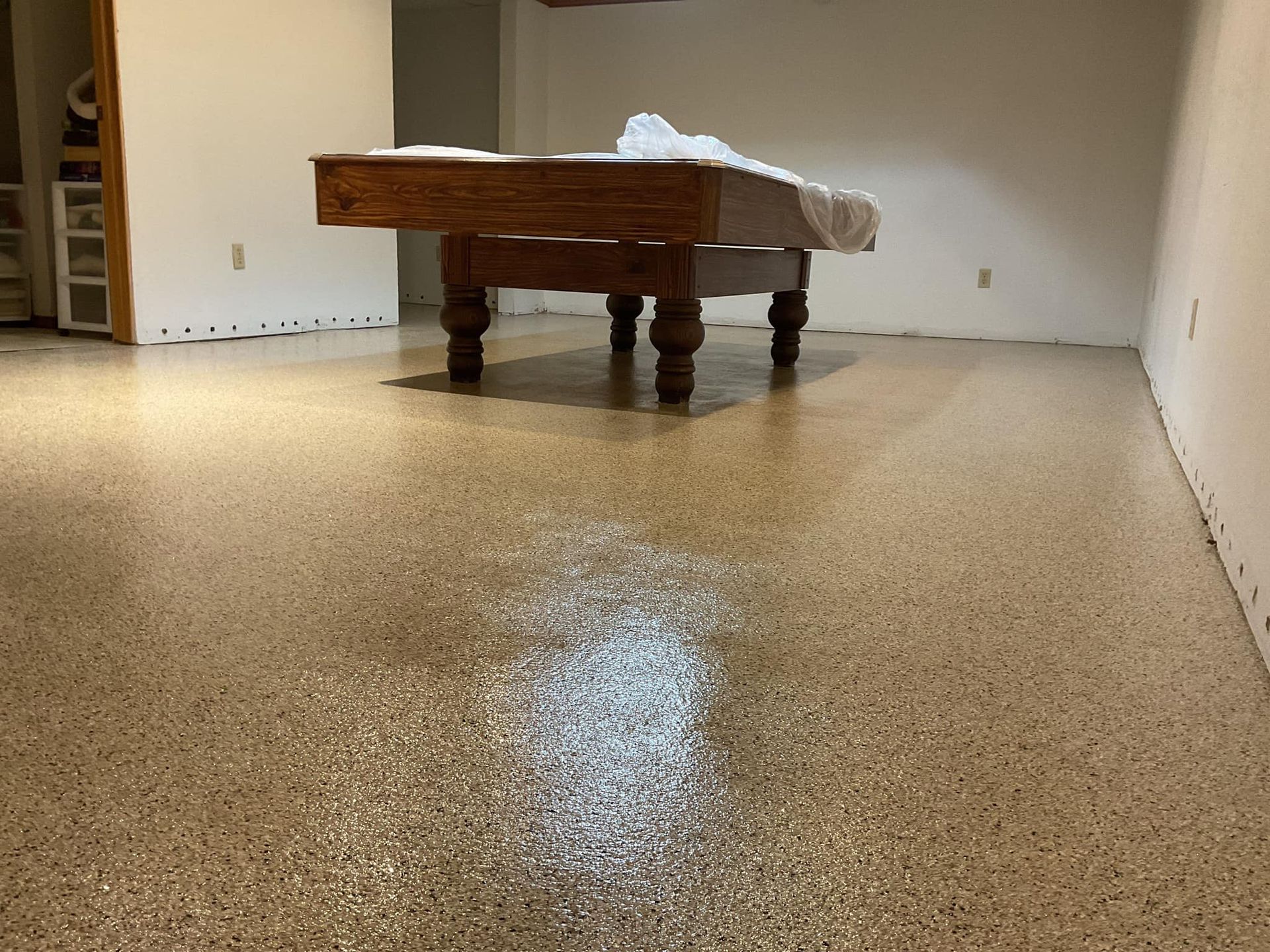A pool table is sitting in a room with a shiny floor.