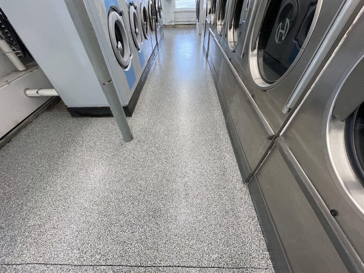 A laundromat with a row of washing machines and dryers.