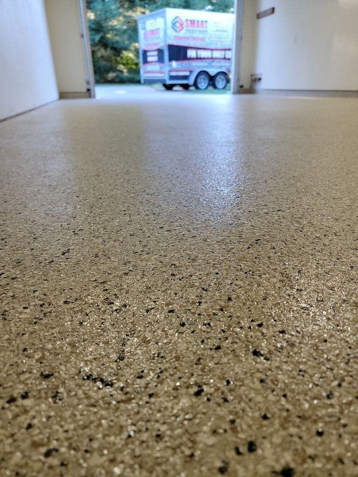 A close up of a shiny concrete floor with a car parked in the background.