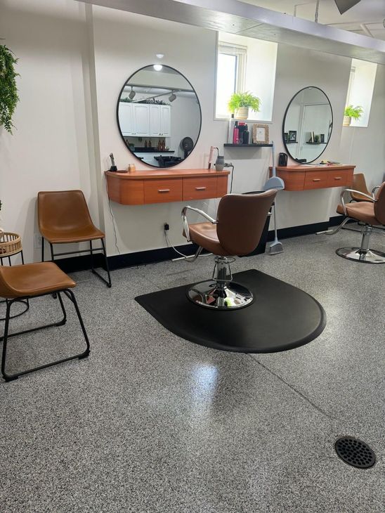 A hair salon with two chairs and two mirrors.