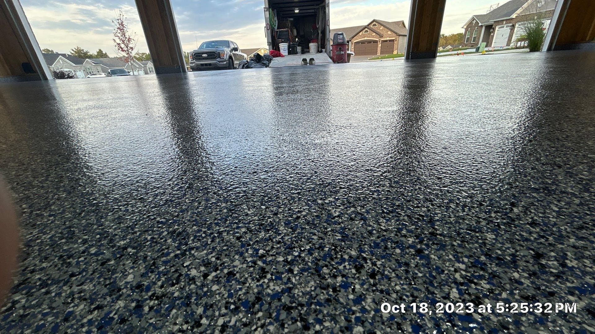 A picture of a garage floor with a truck parked in the background.