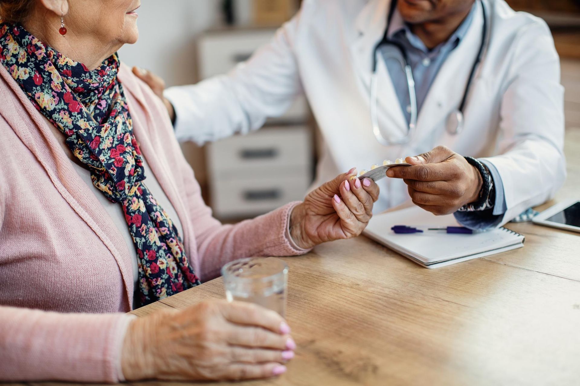 Doctor handing medication to patient across a table in a clinic office
