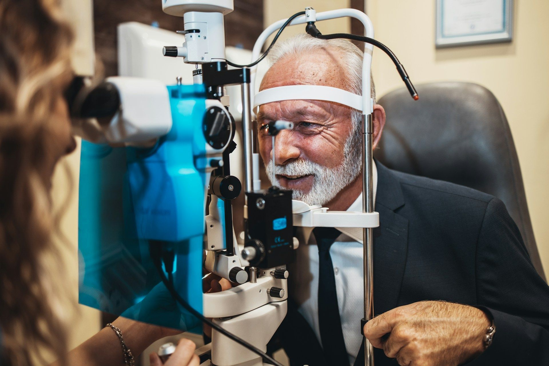 Person undergoing an eye exam with a slit lamp in a clinic, with a doctor assisting nearby