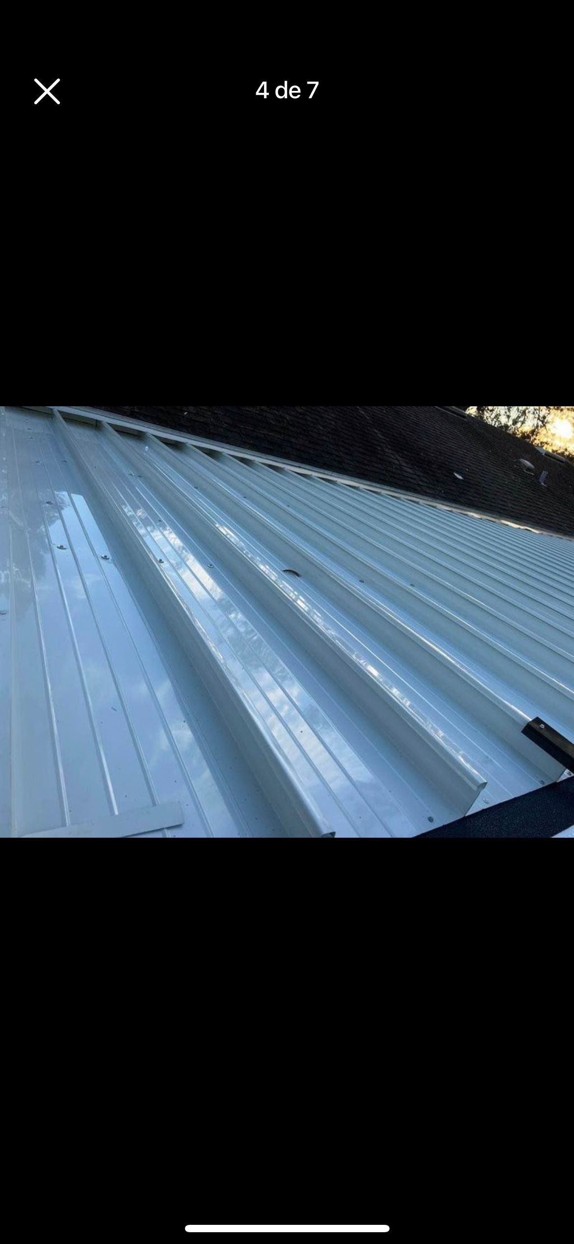 A high-angle view of a white, corrugated metal roof with repeating vertical ridges.