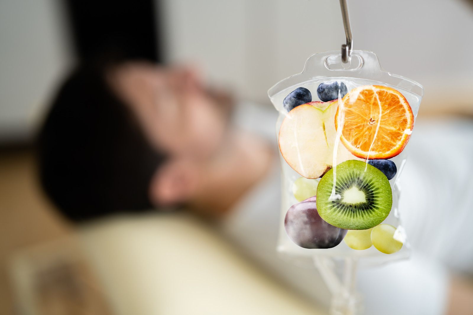 IV bag with fruit slices hanging; blurred person in background.