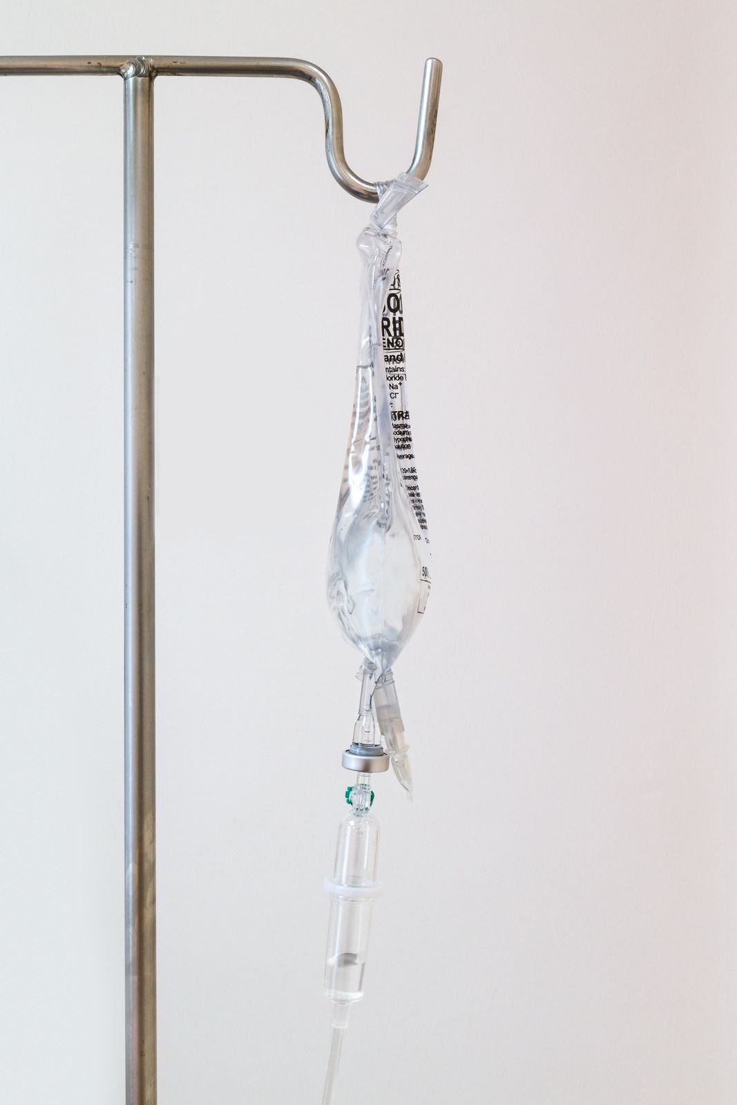 IV bag hanging from a metal stand; clear fluid drips through tubing.
