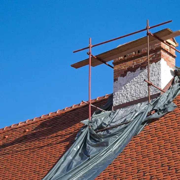 A brick chimney on top of a roof with scaffolding around it