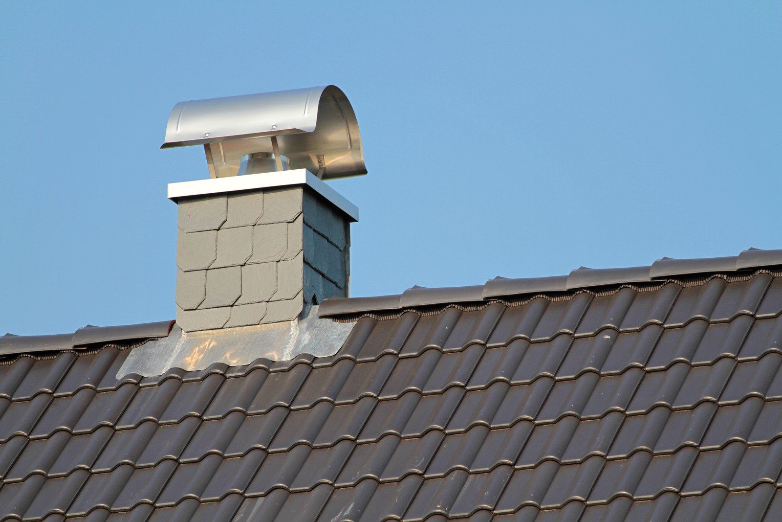 A chimney on top of a brown tiled roof