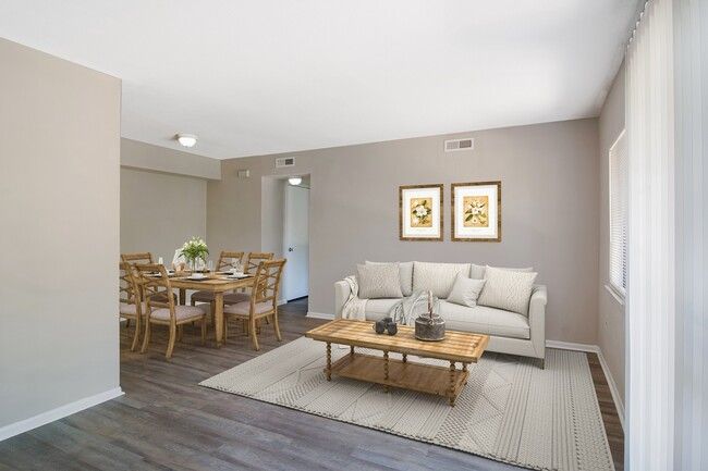 Living room with dining area: tan walls, wood furniture, sofa, rug, and window.