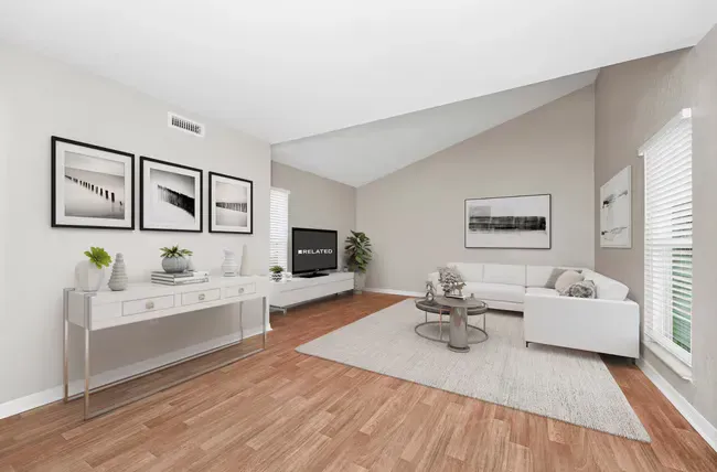 Living room with white furniture, wood floors, and artwork.