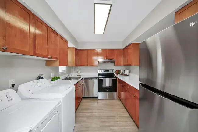 Kitchen with laundry, featuring wood cabinets, stainless steel appliances, and light-colored countertops.