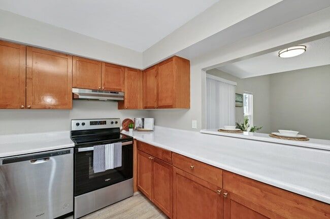 Kitchen with wood cabinets, stainless steel appliances, and white countertops.