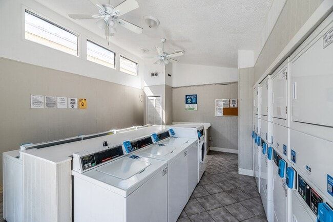 Laundry room with white washers/dryers, gray floor, and ceiling fans.